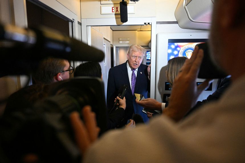 President Donald Trump speaks to journalists aboard Air Force One while travelling from Palm Beach International Airport to Joint Base Andrews on November 30.